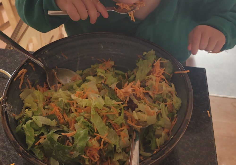 Kleinkind isst Salat aus einer großen Schüssel – Pflanzenvielfalt und Ballaststoffe für Babys und Kleinkinder.
