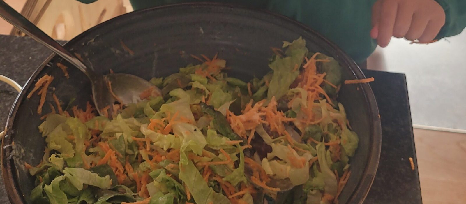 Kleinkind isst Salat aus einer großen Schüssel – Pflanzenvielfalt und Ballaststoffe für Babys und Kleinkinder.
