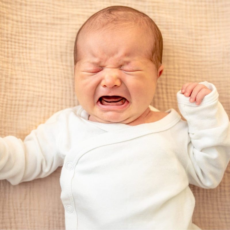 Weinendes Baby liegt auf einer Matratze